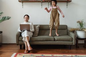 Mom on laptop sitting on couch with daughter